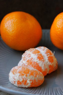 Olgun sarı Mandarin yakın çekim. Bir tabakta tüm mandalina ve soyulmuş mandalina.