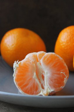 Olgun sarı Mandarin yakın çekim. Bir tabakta tüm mandalina ve soyulmuş mandalina.