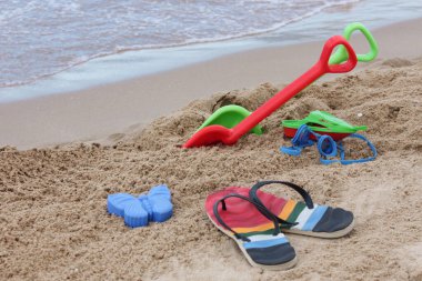 Plaj eğlencesi konsepti. Şapka, yüzme gözlüğü, terlik, kumsalda güneş gözlüğü ve kum.