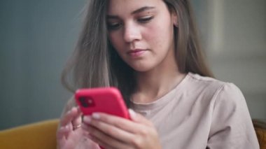 Uzun saçlı kız mesajları kontrol ediyor ya da telefonda pembe kapaklı haberler veriyor. Ekranda aşağı kayıyor. Dudaklarına hafifçe gülümse.
