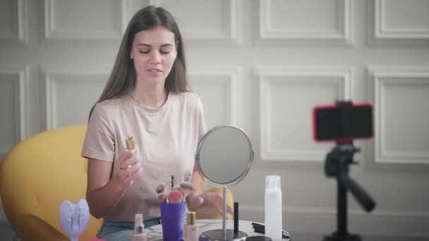 年轻女性博主在网上流连忘返 并对化妆品进行概述 她分享了她对皮肤基金会的看法 — 图库视频影像