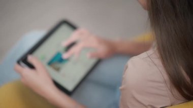 Kız tablet bilgisayarda sörf yaparak boş zaman harcıyor. Genç bir kadın ziyaret etmek istediği güzel yerlerden fotoğraflara bakıyor.