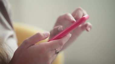Ergen kız evde telefon ve müzikle dinleniyor. Gülümseyen bir kadın sosyal medyada sohbet ediyor ve favori şarkıları kulaklıkla dinliyor.