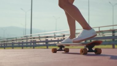 Uzun panoda beyaz ayakkabılı kadın, yakın görüş, genç kız kaykay sürüyor, detaylı görüş, spor hobisi ve yaz tatilinde aktif eğlence, kentsel alanda sportif kişi