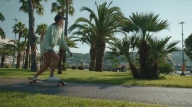 Mutlu genç bir kadın sıcak yaz gününde şehir sokaklarında kaykay sürüyor. Yavaş çekimde kaykaycı, ince ve sportif bir kız tropik bir kasabada dinleniyor.