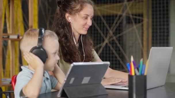 Anne Çocuk Evde Alet Kullanıyorlar Kulaklıklı Bir Kadın Laptopla Çalışırken — Stok video