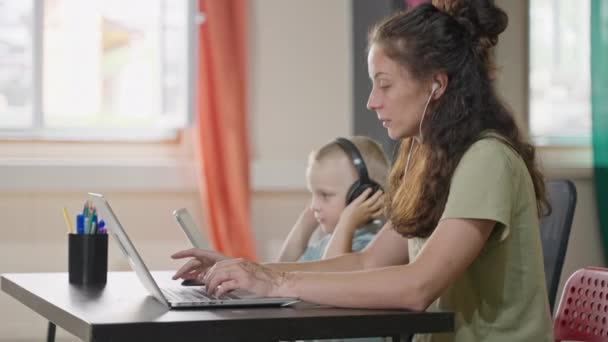 Mãe Trabalhando Remotamente Casa Usando Laptop Pequeno Filho Fones Ouvido — Vídeo de Stock