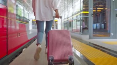 Kadın gezgin tren istasyonunda, dikiz aynasından yürüyor, turist valizini yuvarlıyor, trenle şehirler, toplu taşımacılık ve lojistik arasında seyahat ediyor, kadın anavatanından ayrılıyor.