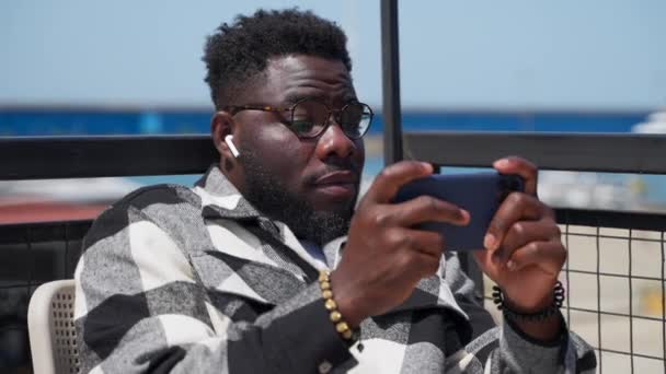 Jonge Zwarte Man Ontspannen Met Gadgets Buiten Hij Kijkt Video — Stockvideo