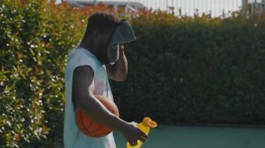 Genç bir Afrikalı Amerikalının basketbol antrenmanını bitirirken ve yüzünü silerken çekilen yavaş çekim.