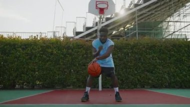 Genç siyah sporcunun basketbol eğitimi, yakışıklı adam açık sahada top kontrolü, yavaş çekim, yaz tatilinde hobi ve eğlence, gençlerin spor aktiviteleri üzerinde pratik yapıyor.