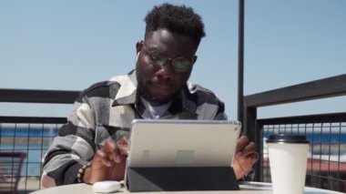 Zeki profesyonel it uzmanı ve programcı seyahat sırasında uzaktan çalışıyor, kafede siyah bir adamın portresi, ücretsiz kablosuz internet bağlantısı olan tablet tablet sörf yapıyor, Afrikalı Amerikalı adam internette sörf yapıyor.