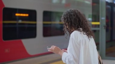 Genç bir kadın tren istasyonunda beklerken dijital bilgisayar kullanıyor. Banliyö yaşam tarzı