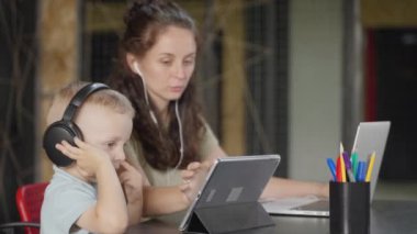 Anne uzaktan çalışacak, bu yüzden tablet bilgisayarda oğlu için çizgi film ya da uygulama seçiyor. Çocuk sessizken ve bir şeylerle meşgulken çalışabilir.