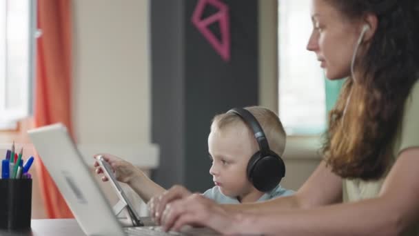 Mujer Con Auriculares Usando Laptop Hablando Por Negocios Hijo Pequeño — Vídeos de Stock