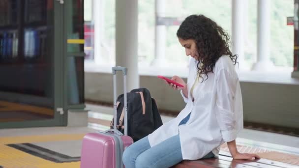 Giovane Viaggiatrice Attesa Treno Sulla Piattaforma Seduta Panchina Con Bagaglio — Video Stock