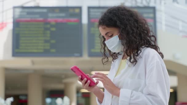 Kvinna Med Ansiktsmask Kontrollerar Tidtabellen App Smartphone Jämföra Med Terminalschemat — Stockvideo