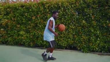 Basketbol antrenmanı açık havada, genç siyah oyuncu top fırlatma, top sürme, yavaş çekim, spor ve hobi yapıyor.