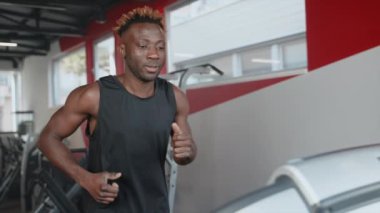 Spor salonundaki koşu bandında spor yapan Afrikalı Amerikalı bir adamın yavaş çekim çekimi. Dayanıklılık artıyor