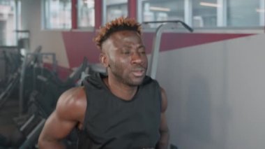 Koşu bandında koşan odaklanmış bir sporcunun yavaş çekim ön çekimi. Afrikalı Amerikalı sporcu dayanıklılık kazanmak için kardiyo çalışması yapıyor.