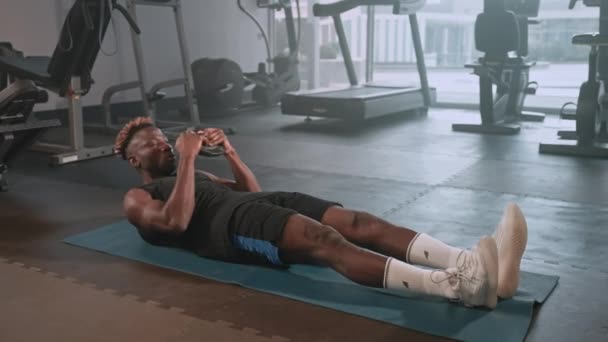 一个黑人运动员在健身俱乐部的垫子上做仰卧起坐的慢镜头 从事腹肌运动的运动员 — 图库视频影像