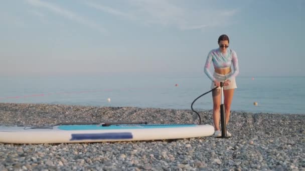Strzał Zwolnionym Tempie Kobiety Żwirowym Brzegu Pompującej Deskę Surfingową Pompą — Wideo stockowe