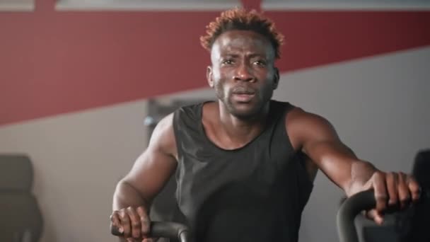 Geconcentreerde Afro Amerikaanse Man Met Gespierde Armen Traint Stationaire Fiets — Stockvideo