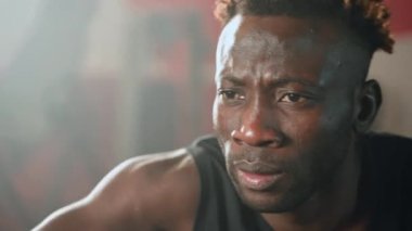 Spor salonundaki Afrikalı sporcunun yakın plan portresi. Genç siyahi adam spor salonunda egzersiz yapıyor. Yorgun bir sporcunun yüzü.