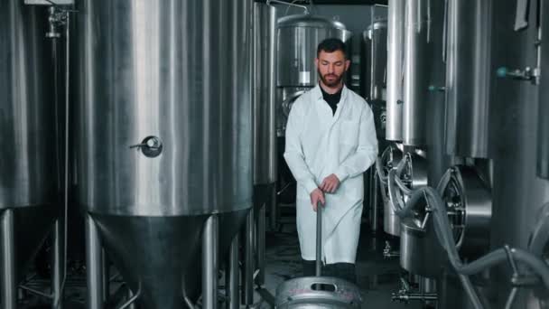 Пивоварний Технолог Переміщує Бочку Пивом Цеху Між Циліндрично Конічними Резервуарами — стокове відео