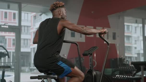 Homem Negro Forte Está Treinando Bicicleta Exercício Ginásio Girando Pedais — Vídeo de Stock