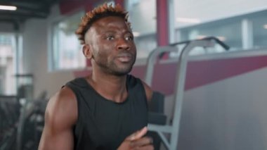 Spor salonunda yoğun kardiyo eğitimi, atletik siyah adam koşu bandında koşuyor, orta boy portre, sağlıklı yaşam tarzı ve aktif spor hobisi, iyi hissetmek için egzersiz.