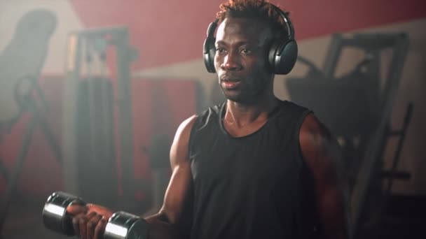 Gespierde Zwarte Man Met Hoofdtelefoon Traint Alleen Fitnessruimte Tilt Halters — Stockvideo