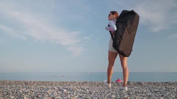 Młoda Kobieta Dużym Plecakiem Spaceruje Żwirowym Wybrzeżu Niosąc Sprzęt Sportowy — Wideo stockowe