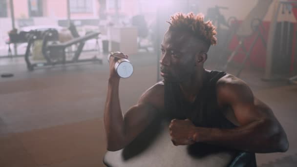 근육질 남자는 체육관에서 훈련하고 있으며 덤벨을 센터에서 일하고 아프리카 미국인 — 비디오