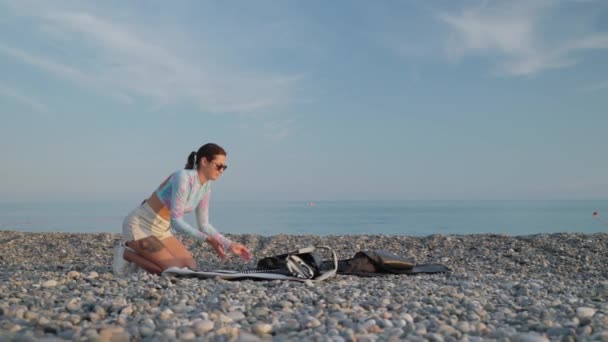 Młoda Aktywna Kobieta Rozpakowuje Deskę Wstawania Paddleboarding Sup Żwirowej Plaży — Wideo stockowe