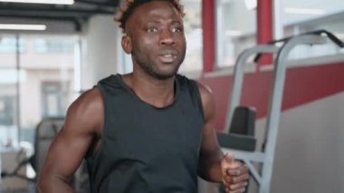Genç siyah atlet, artan dayanıklılık ve spor salonunda koşu bandında, kardiyo çalışmasında çalışıyor. Düzenli sporlara ayak uydurmak