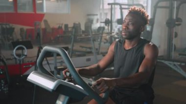 Sportif Afrikalı Amerikalı adam spor salonunda tek başına antrenman yapıyor, staj bisikleti eğitimi, sağlıklı yaşam tarzı, spor salonunda aktif fiziksel egzersiz, erkek spor hobisi