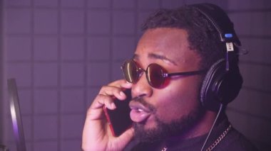 Yavaş çekimde, profesyonel müzik stüdyosunda şarkı molası verdiğinde konuşan Afrikalı Amerikalı bir adamın yakın plan çekimleri.