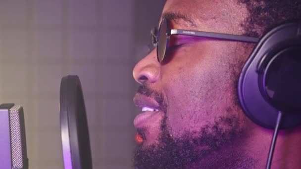 一个黑人在音乐工作室对着话筒唱歌的特写镜头 专业歌手录制新歌 — 图库视频影像