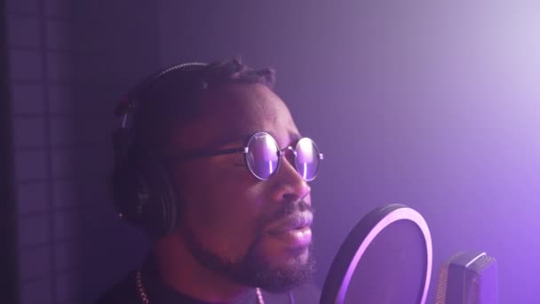 英俊潇洒的黑人男子在录音室的隔离室里唱着情歌 录音专辑 戴着圆圆的太阳镜的时髦非洲裔美国人的肖像 — 图库视频影像