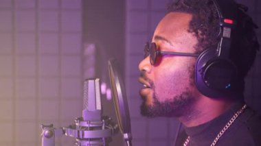 Ses stüdyosundaki bir mikrofona romantik bir şarkı söyleyen siyahi bir adamın yakın plan çekimleri. Profesyonel müzisyen yavaş çekimde yeni bir parça çalıyor. Müzik üretimi