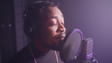 Müzik stüdyosunda romantik bir beste yapan siyahi bir adamın yakın çekim yavaş çekimi. Sözlü albüm için yeni şarkı kaydediliyor