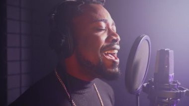 Afrikalı Amerikalı bir şarkıcının müzik stüdyosunda romantik bir aşk şarkısı söylerken yavaş çekim. Kapalı gözlerle performans sergileyen adam duygularla yaşıyor.