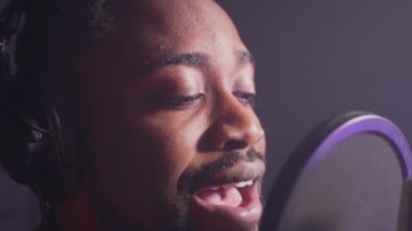 Ses stüdyosunda romantik bir şarkı söyleyen siyahi bir adamın yakın plan çekimi. Profesyonel müzisyen yeni bir şarkı söylüyor, ağır çekimde. Müzik üretimi
