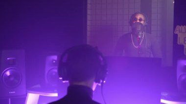 Afrika kökenli Amerikalı şarkıcı ve sesçinin yeni bir şarkı yaratmaya çalışmasının yavaş çekimi. Ses stüdyosunda müzik kaydetme süreci, mor ışıkla görünüm