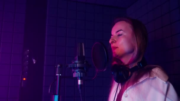 열정적 활기찬 가수가 스튜디오에서 움직임으로 노래를 합니다 여인은 감정적으로 마이크로폰 — 비디오