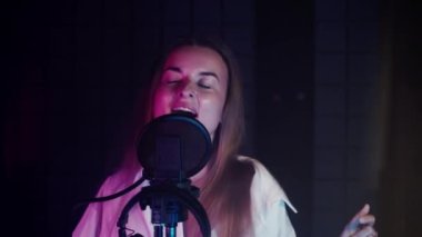 Duygusal yetenekli şarkıcı kadın yüksek sesle şarkı söylüyor ses kayıt stüdyosunda, izolasyon odasında portre, ses becerileri ve yetenek, yeni bir müzik albümü yaratıyor.