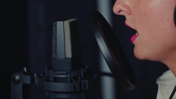 가수인 여배우는 녹음실에서 음향을 하거나 마이크와 여성의 얼굴을 클로즈업하거나 노래를 — 비디오