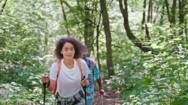 Gülümseyen rahat bir çift orman yolunda birlikte yürüyüş yapıyor. Çeşitlilik, genç erkek ve kadının vahşi yerlerde doğayı keşfetmesi. Turizm, seyahat, yürüyüş, macera, keşif konsepti.