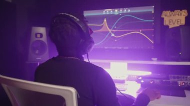 Siyah adam modern müzik kayıt stüdyosunda çalışıyor, ses mühendisi dijital ses çalışma istasyonunda, profesyonel müzisyen elektronik müzik yapıyor, besteci düzenleme yapıyor.